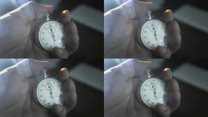 一个男人手中的秒表。一名男子按下老式运动金属第二手表的按钮。倒计时，活动前的计时器