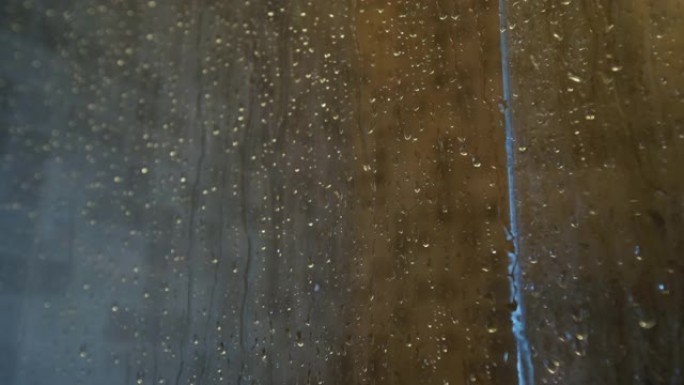 脚在瓷砖玻璃后面的淋浴里。瀑布，玻璃出汗，特写，慢动作