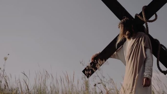 耶稣肩膀上站着十字架。风在吹。草在swways