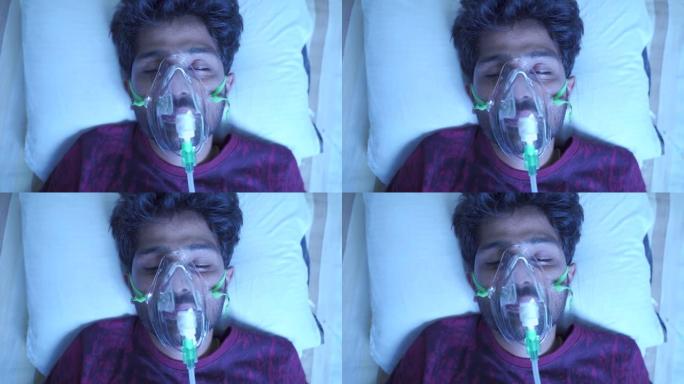 由于新型冠状病毒肺炎呼吸困难或呼吸急促而在医院用呼吸机或氧气浓缩器面罩呼吸的年轻人的俯视图-冠状病毒