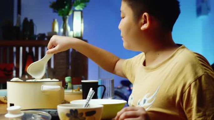 亚洲男孩晚上在家与家人一起吃sha锅或寿喜烧，生活方式观念。