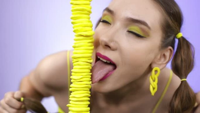 一个开朗的女孩舔着黄色的糖果塔