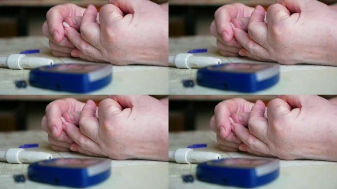 在家里用血糖仪进行血液检查后，糖尿病患者的手特写。仪表不在桌子上。女人用棉签止住手指上的血。