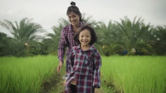 年轻的亚洲母女在绿茵场上奔跑。