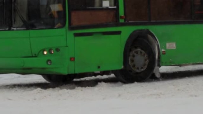 冬天。公共城市交通巴士在城市的雪道上行驶。慢动作降雪。交通恶劣的天气条件，暴风雪。道路交通事故的危险