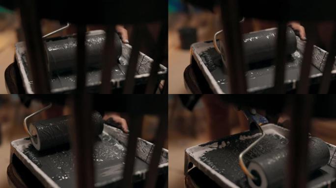 椅子的特写镜头，上面放着一个托盘，一个装有灰色油漆的容器，一个拿着大滚筒的女人的手在平滑的运动中获得