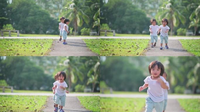 周末早上，亚洲中国双胞胎男婴在公园草坪上走向相机