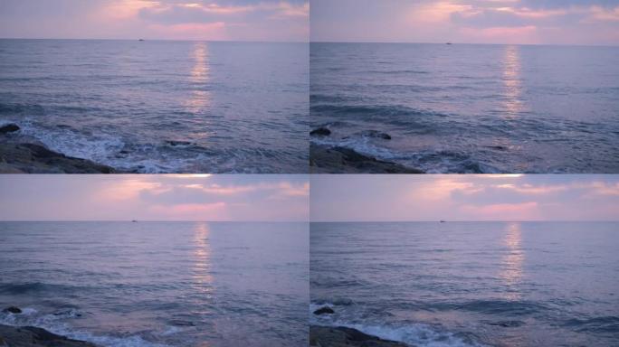 海浪在海上轻拂。有岩石的海岸 .. 鹅卵石很小。日落。地平线。