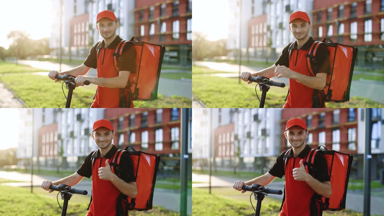 肖像微笑的美国男子快递食品递送站在热背包，电动滑板车看着相机，露出拇指。积极送货员工人交付在线订单客
