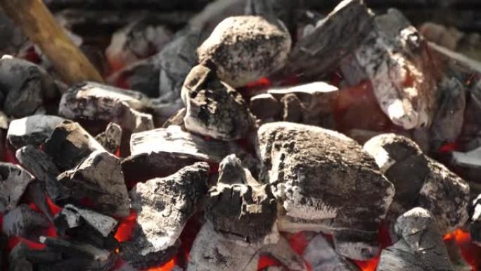 慢动作速度特写人的场景用树枝挖在燃烧的木炭堆上使灰烬和火花碎片散落炸毁