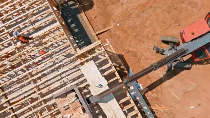 一辆木工被一辆起重卡车叉车在建筑材料中抬起，一堆木板木构架了一个新家