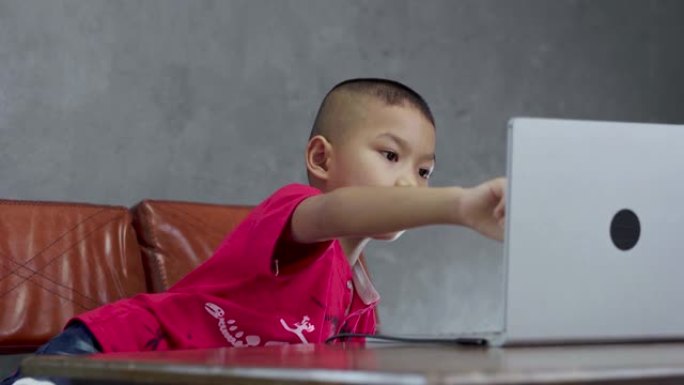 小男孩在家里寻找笔记本电脑进行电子学习。