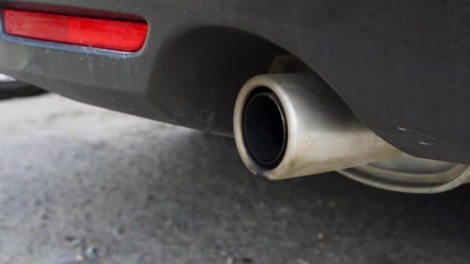 特写汽车的排气管，启动时水滴从排气管中飞溅。