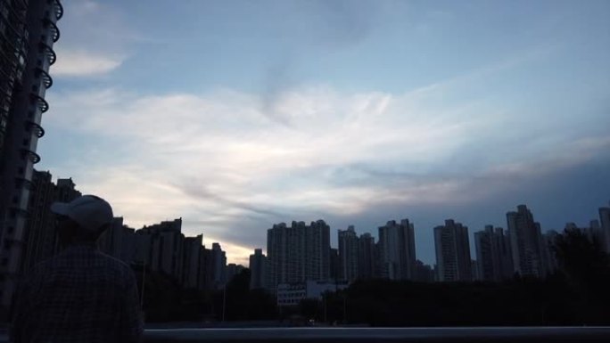 中国老人快乐地在上海高楼之间的河边放风筝，在傍晚的夕阳与美丽的云朵，中国