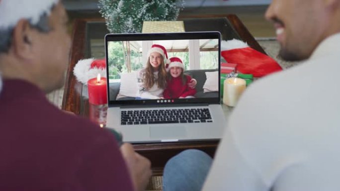 微笑的混血儿父子使用笔记本电脑与屏幕上的幸福家庭进行圣诞节视频通话
