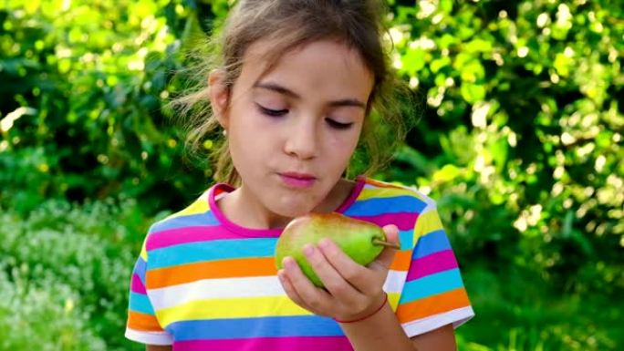 孩子在花园里吃梨。选择性聚焦。