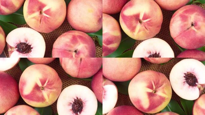 俯视图旋转新鲜的桃子与切片特写，白色的桃子放在花园的木桌上的竹席上。