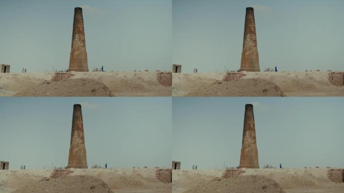巴基斯坦的一个砖厂，使用奴隶劳工。沙滩上有一辆空的拖车。背景上有烟的大砖管。慢动作