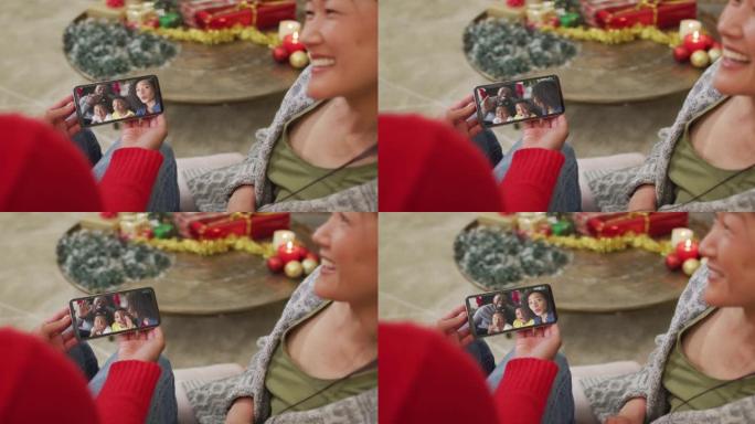 微笑的亚洲夫妇使用智能手机与家人在屏幕上进行圣诞节视频通话