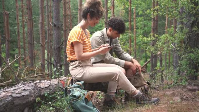 微笑的年轻徒步旅行者使用智能手机上的GPS地图在树林里导航