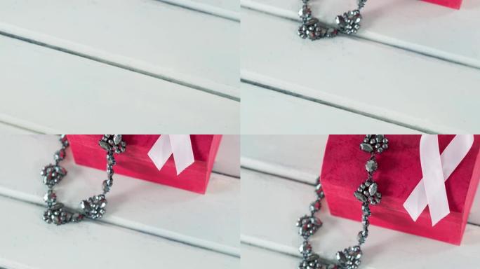 粉红珠宝粉红盒子，丝带和项链在白色木制背景上的动画