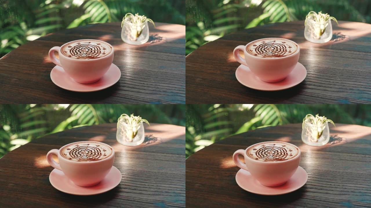一杯热卡布奇诺咖啡，带拿铁艺术，放在热带绿色的木桌上