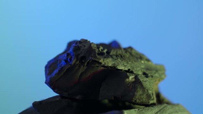 木炭。蓝绿色屏幕背景上的黑色木炭。用于烹饪烤架或工业。天然木炭。通过强烈加热木材产生的黑碳。烧烤。
