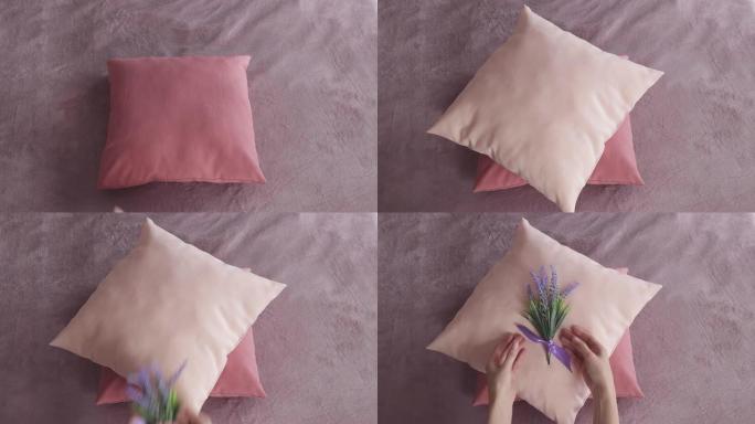 女性双手的俯视图将彩色枕头堆积在床上，并在上面放一束薰衣草。专业女仆通过用鲜花装饰床为客人准备酒店房