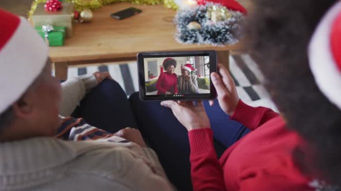 非裔美国母亲和女儿使用平板电脑与屏幕上的家人进行圣诞节视频通话
