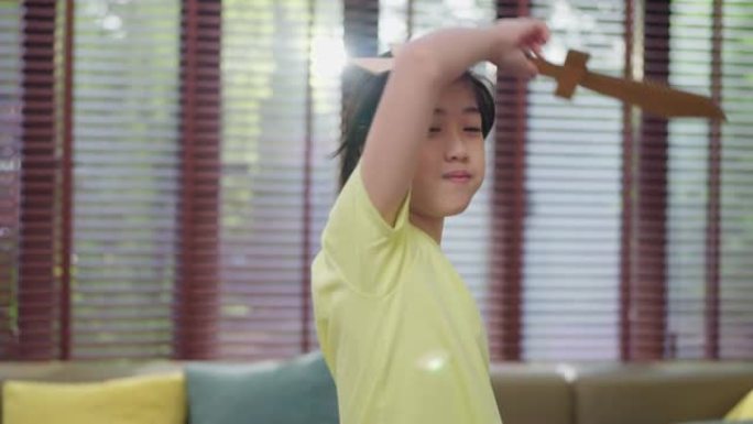 亚洲小王子童子扮演角色，小男孩扮演国王手持纸剑微笑与开朗有趣的纸纸板游戏休闲爱好游戏在家待在家里概念