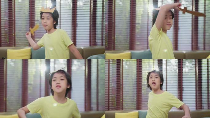 亚洲小王子童子扮演角色，小男孩扮演国王手持纸剑微笑与开朗有趣的纸纸板游戏休闲爱好游戏在家待在家里概念