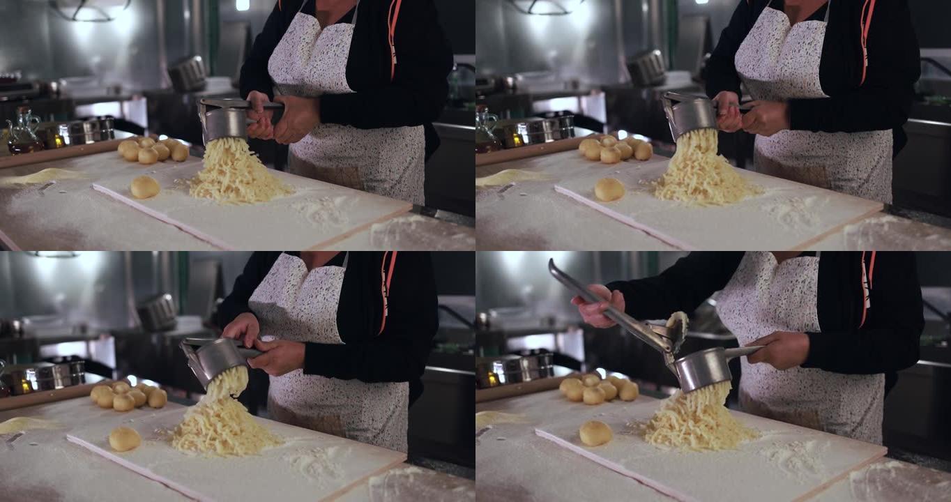 妇女在意大利面工厂内使用马铃薯压榨机制作新鲜手工汤团
