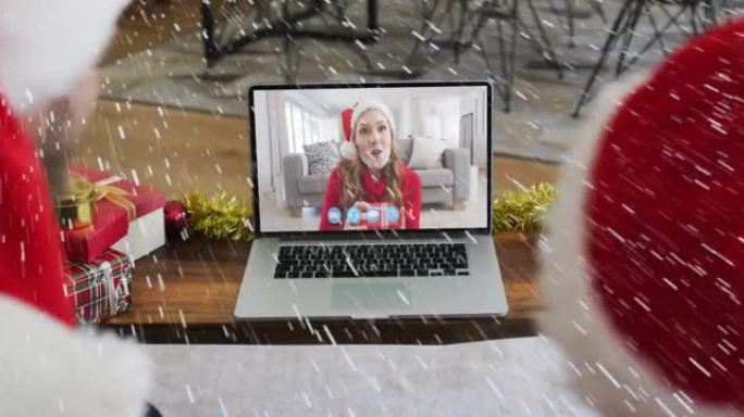 在与家人的笔记本电脑视频通话中，雪花落在圣诞老人帽子上的微笑夫妇身上的动画
