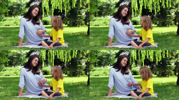 一位怀孕的母亲用手掌遮住女儿躺在肚子上的手