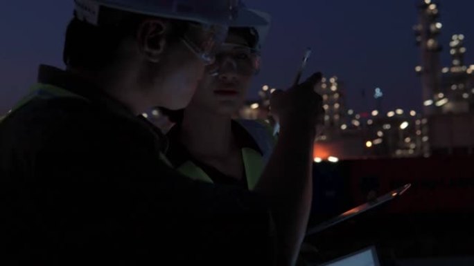 团队工程师或其他专业人员在石油和天然气或其他工业现场工作的视频，晚上使用数字平板电脑工作