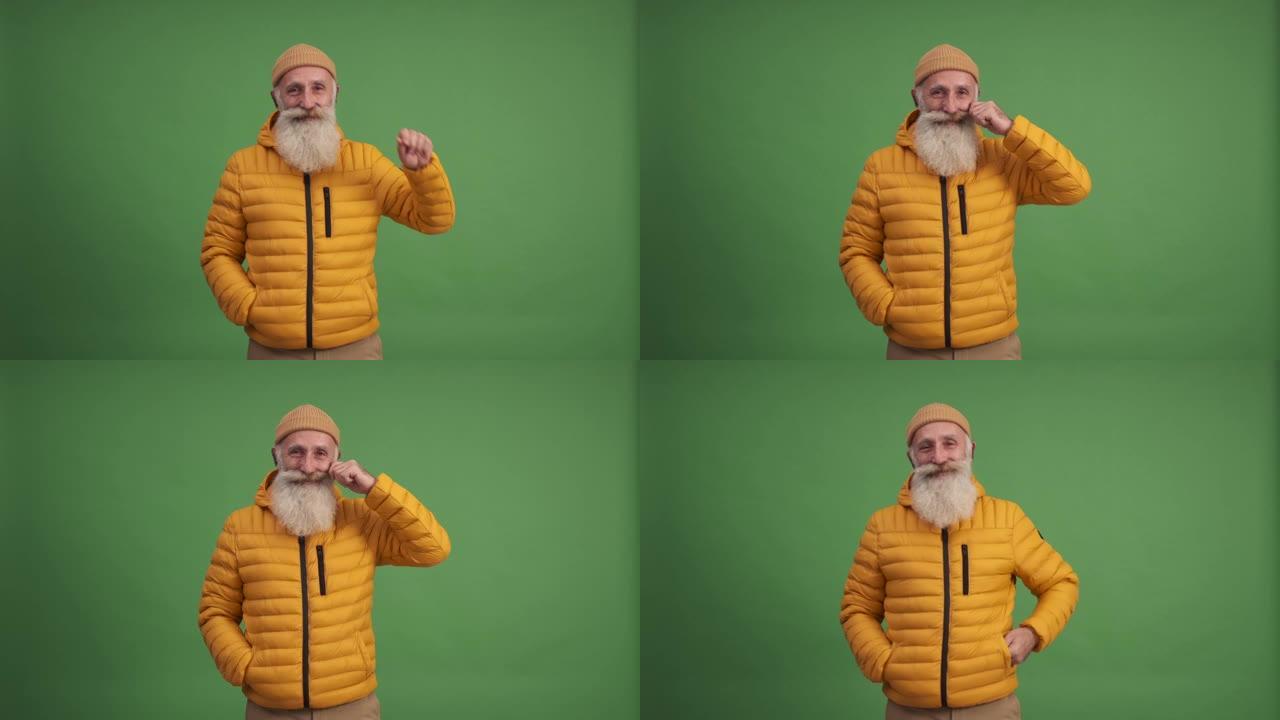 一位老人微笑着，捋了捋胡子，看着摄像机。绿色背景。一个人