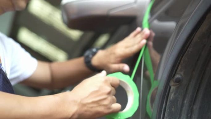 在抛光汽车细节之前，铜手在汽车表面使用绿色遮蔽胶带