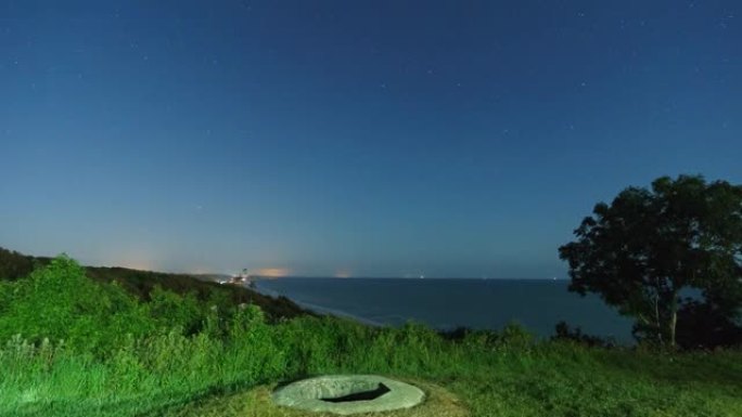 移动的夜空在奥马哈海滩上，来自WN 60的掩体被前景上升的月亮照亮，背景是海滩上的高潮，法国滨海科勒