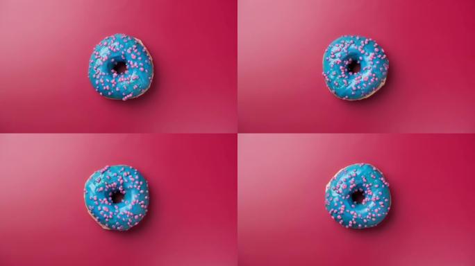 蓝色糖霜甜甜圈，粉红背景。甜点。
