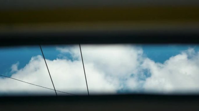 通过行驶中的汽车打开的天窗拍摄天空。车内全景玻璃天窗