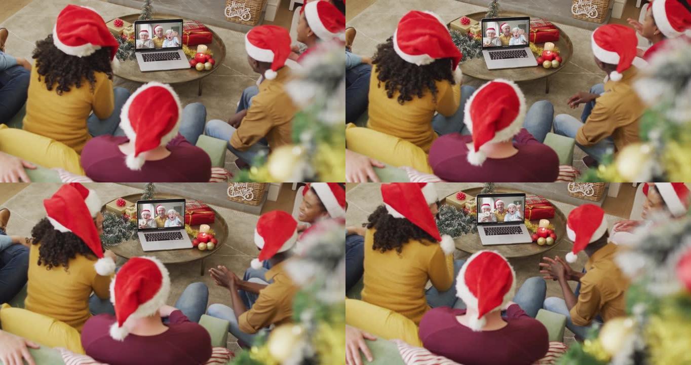带有圣诞老人帽子的多元化家庭使用笔记本电脑进行圣诞节视频通话，屏幕上有微笑的家庭