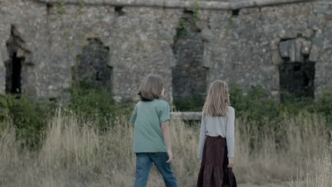 姐妹和兄弟在古老的废墟城堡中漫步的背景图