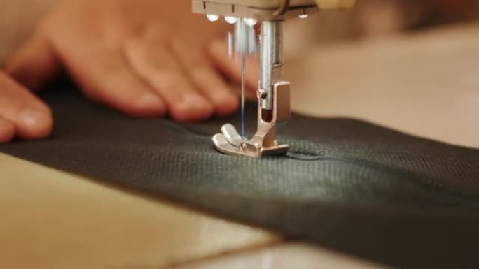 裁缝的手是用白色工业缝纫机缝制拉链 (拉链) 的裆黑色裤子特写。