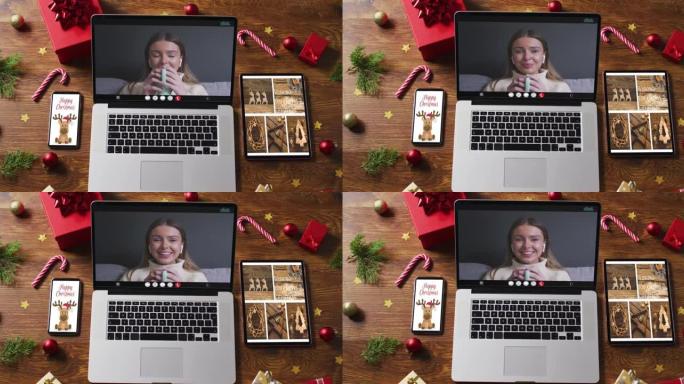 快乐的白人妇女在笔记本电脑上进行视频通话，配备智能手机，平板电脑和圣诞节装饰品