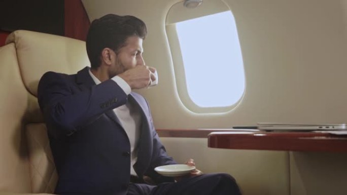 男子乘坐私人飞机，喝咖啡。
