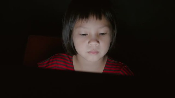 女孩在晚上使用笔记本电脑或数字平板电脑设备。