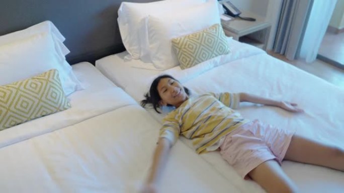 假期，微笑的亚洲女孩躺在酒店的床上，生活方式理念。