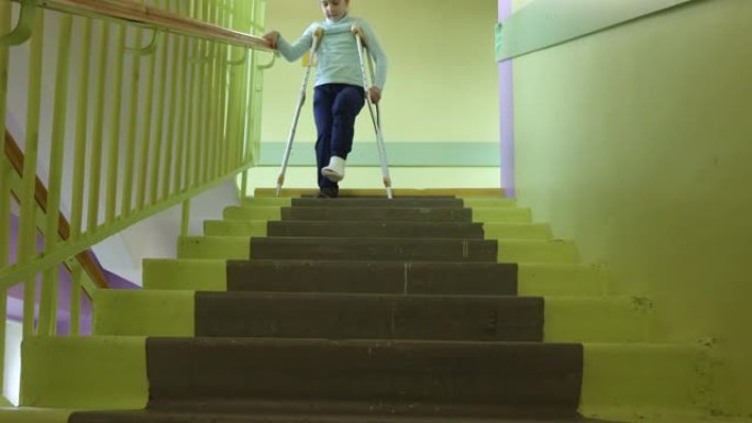 孩子在医院拄着拐杖走下楼梯。女孩的一条腿骨折了。