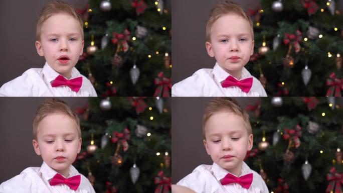 穿着白衬衫，领结的顽皮男孩的肖像，吃糖果，一年都表现不佳，所以圣诞节不会收到圣诞老人的礼物