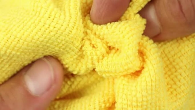 手测试和拉伸黄色超细纤维除尘布，吸水合成织物质地的特写视图